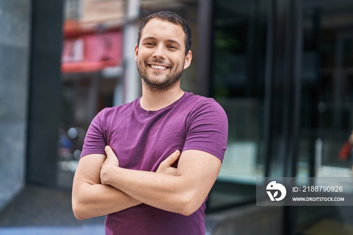 Young man smiling confident standing with arms crossed gesture at street