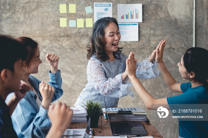 Group of Asian businesspeople raising their hands, rejoicing with the achievements as set forth, congratulating the accomplished work together. Business people high five.