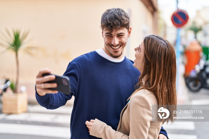 Mand and woman couple hugging each other make selfie by smartphone at street