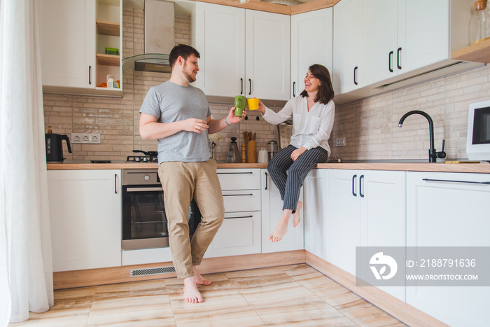 smiling man with woman at kitchen drinking tea