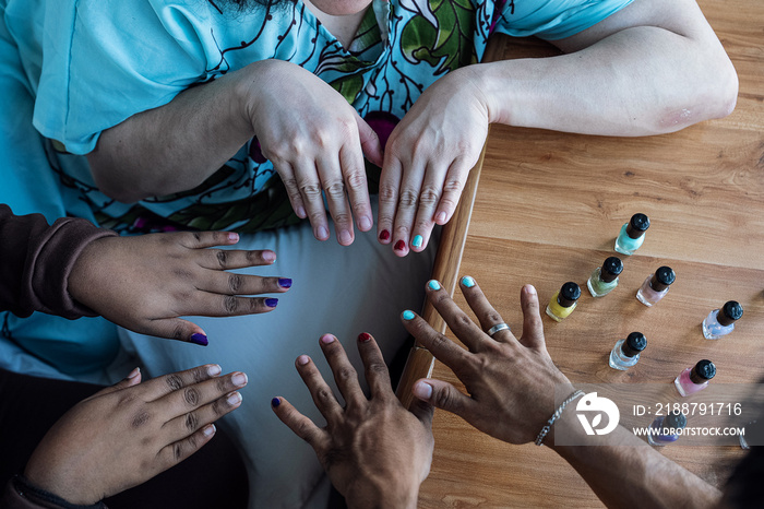 Three friends painting their nails together at home