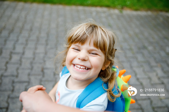 Mother accompanies preschool girl to daycare or school. Mom encourages student child to accompany her to school. Caring mother holds daughter hand as she goes to school. Happy positive girl.