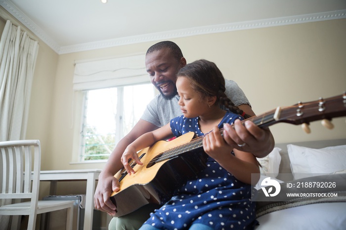 Father teaching his daughter to play the guitar