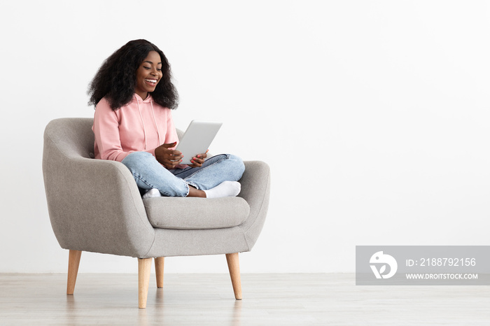 Cheerful african american young lady using digital tablet