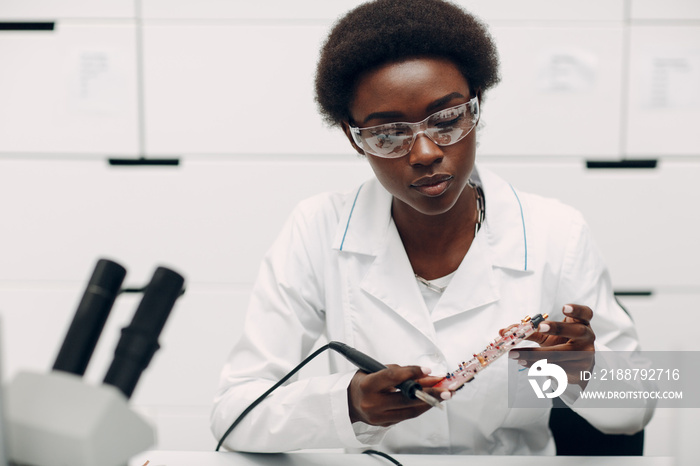 Scientist african american woman working in laboratory with soldering ironand checking electronic plate board. Research and development of electronic devices by color black woman.