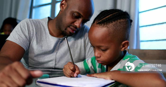 Father helping son with homework at home. African black dad mentoring little boy