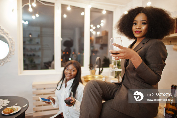 Two african american female friends women spending time at kitchen with wine. Black girlfriends  relaxing at home.