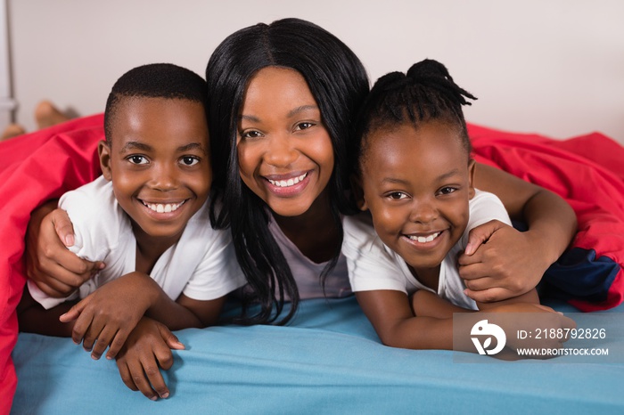 Portrait of smiling woman with children lying on bed