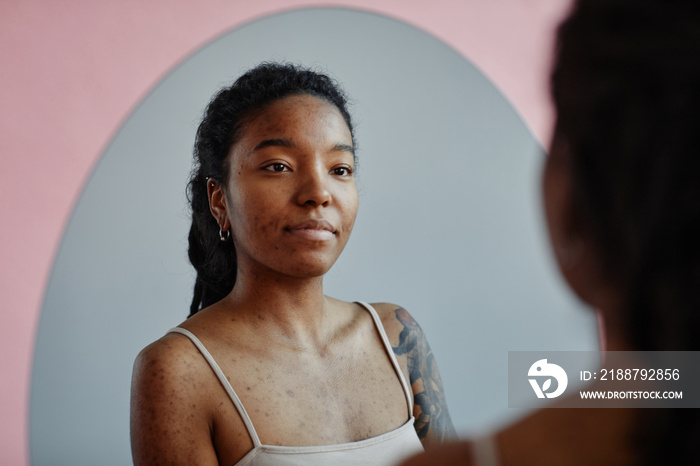 Young black woman looking in mirror smiling