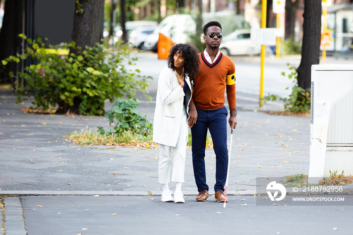 Woman Assisting Blind Man On Street