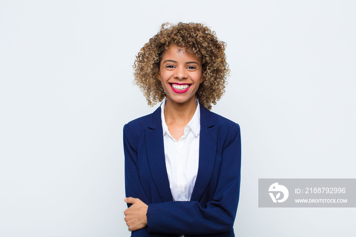 young woman african american laughing shyly and cheerfully, with a friendly and positive but insecure attitude against flat wall