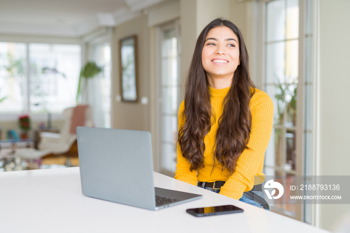 Young woman using computer laptop looking away to side with smile on face, natural expression. Laughing confident.