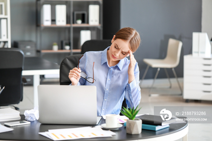 Young woman suffering from headache in office