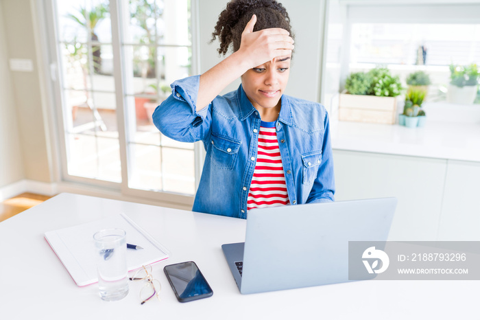 Young african american student woman using computer laptop stressed with hand on head, shocked with shame and surprise face, angry and frustrated. Fear and upset for mistake.