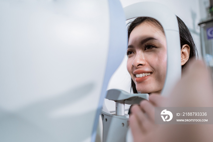 a beautiful woman is undergoing an examination using an eye examiner in the eye clinic room