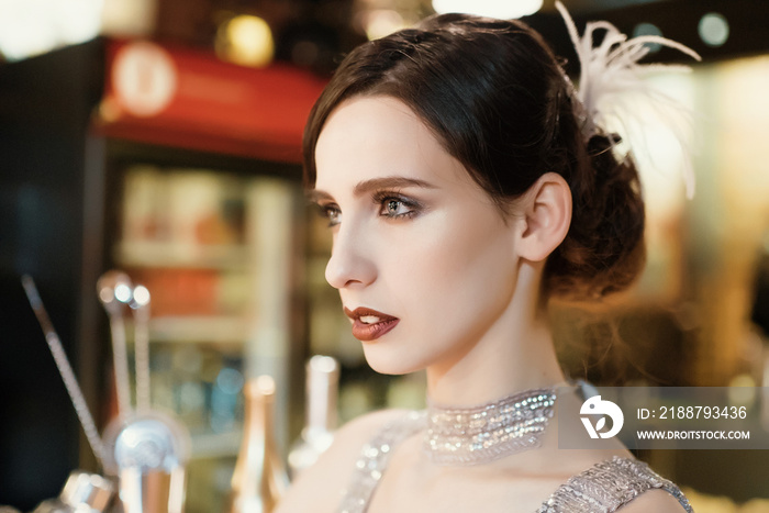 Close-up portrait of a young attractive woman in a 1920s style at the bar. Model with a beautiful make-up