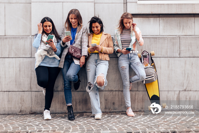 Young girls having fun using smartphones outdoors in the city - Focus on faces