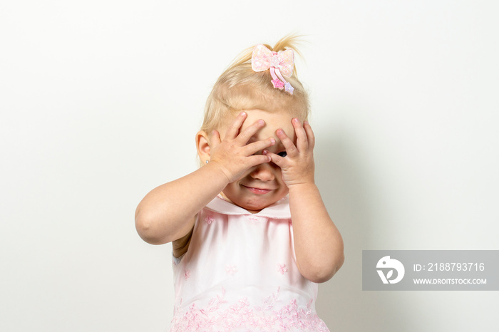 Little child covers his face with his hands on a light background. Concept of fear, fear, domestic violence, the game of locks