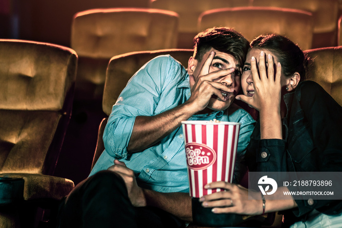 A couple of lovers watching movie shock and eyes close in the movie theater cinema.