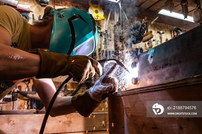 Metalworker operates spot welder indoors. A closeup view of a skilled tradesman operating a metal inert gas welder to join the corners of two steel beams. Process of a metalworker at work.