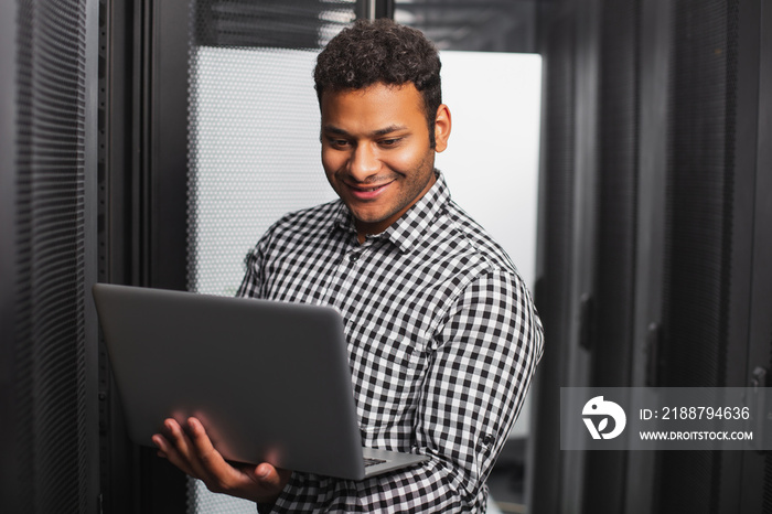 Technical support. Cheerful IT guy using laptop and smiling