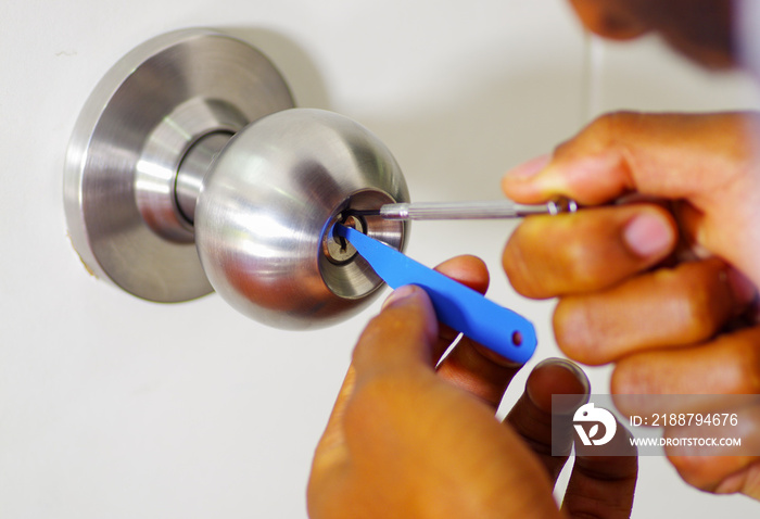 Closeup hands of locksmith using pick tools to open locked door