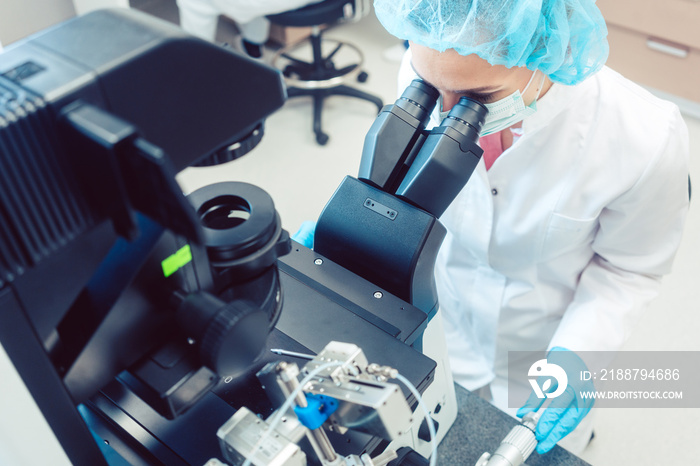 Woman doctor working on manipulator fertilizing human eggs