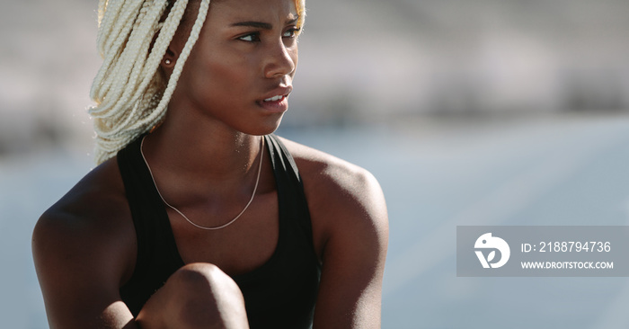 Portrait of a female athlete sitting on running track