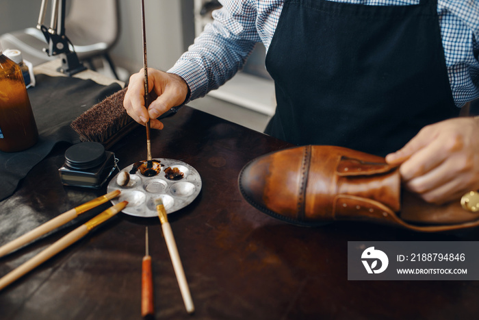 Bootmaker with brush tints shoes, footwear repair