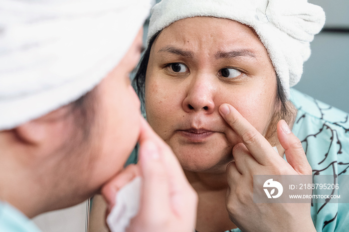 Plus size female examining her skin in the mirror