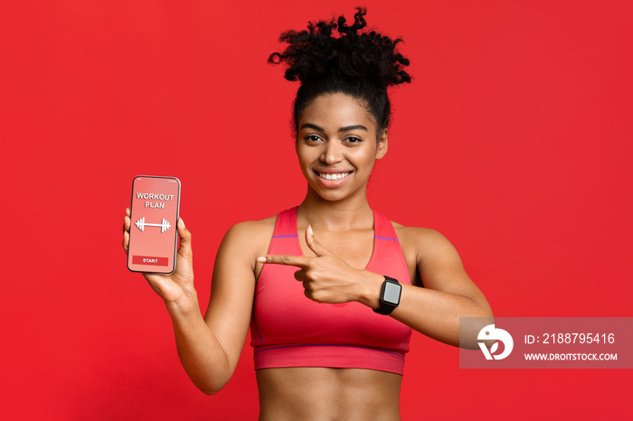 Afro fitness girl pointing at workout application on phone screen