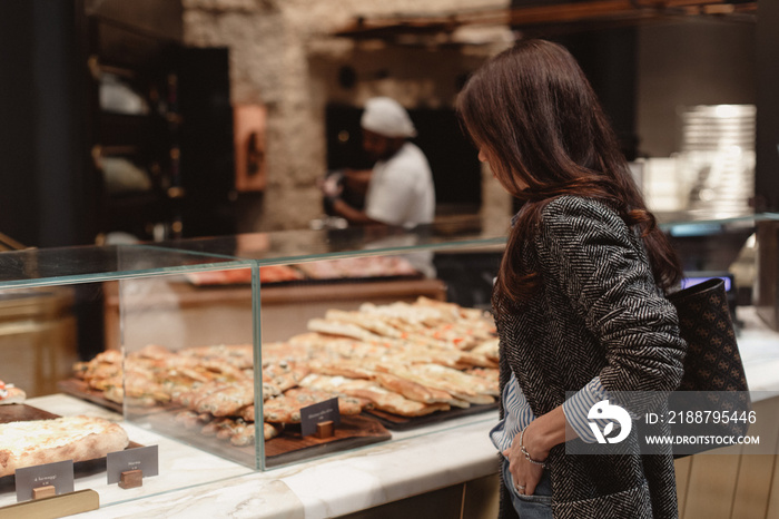 Beautiful girl near a shop window with bakery products.