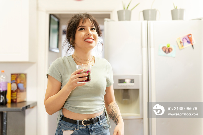 Young woman drinking soda in kitchen