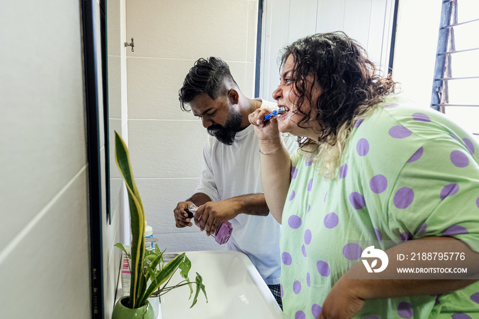 Couple brushing their teeth in the bathroom in the morning