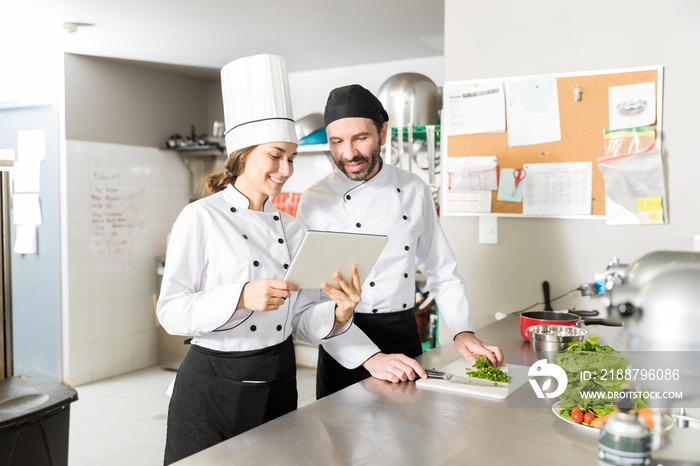 Hispanic Chefs Using Digital Tablet In Kitchen