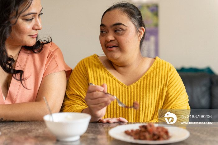 Mother eating dinner with down syndrome daughter at home