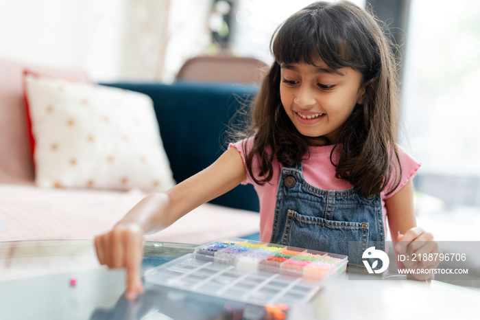 Little girl playing with beads in living room