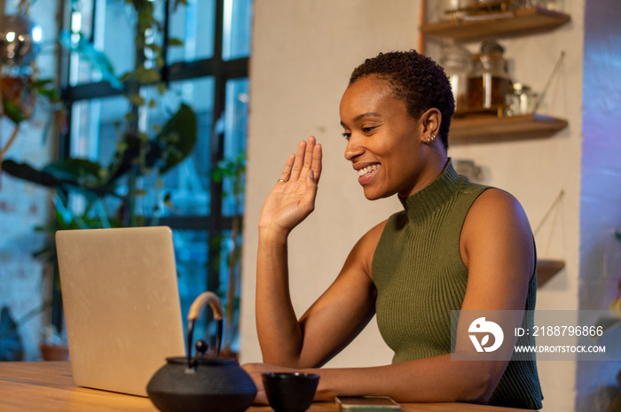 Smiling woman waving during video call on laptop