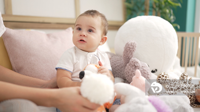 Adorable toddler sitting on sofa with dolls at home