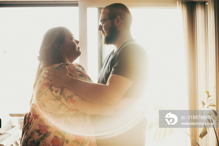 couple embracing in front of window