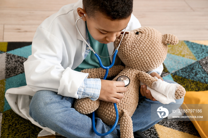 Cute little African-American boy playing doctor at home