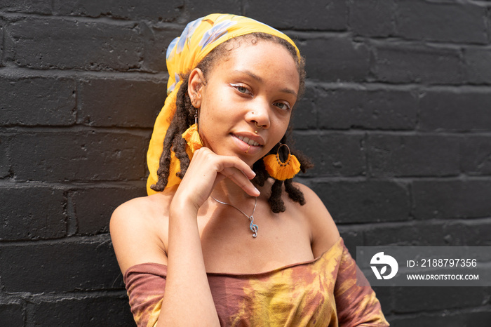 Portrait of young woman standing against brick wall