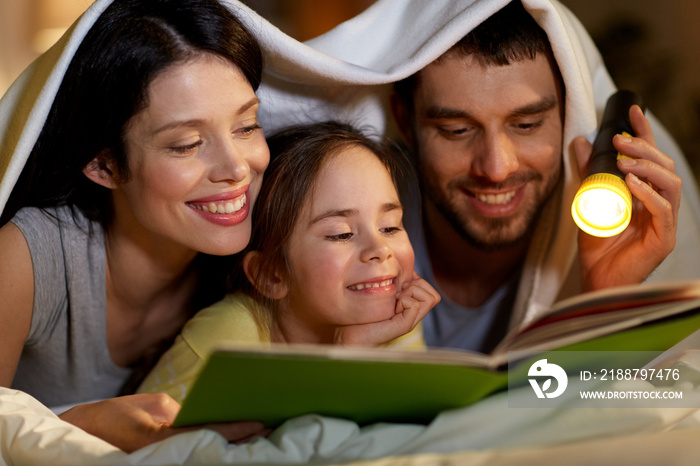 happy family reading book in bed at night at home