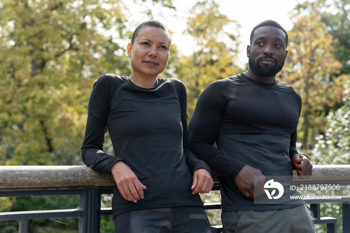 Portrait of athletic man and woman relaxing in park