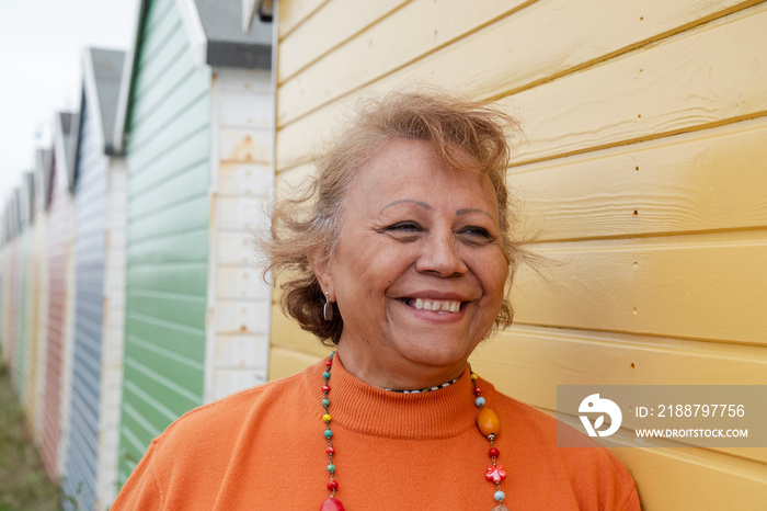 Portrait of smiling senior woman standing by beach hut