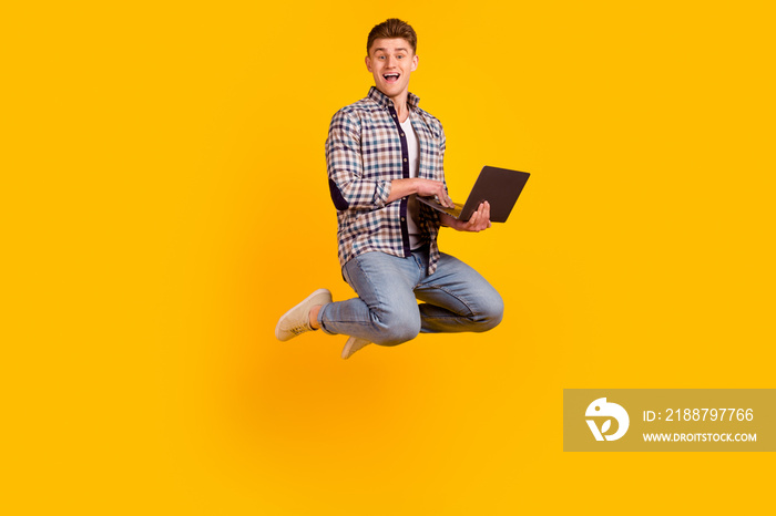 Full size profile side photo of young man jump use laptop marketer economist isolated over yellow color background