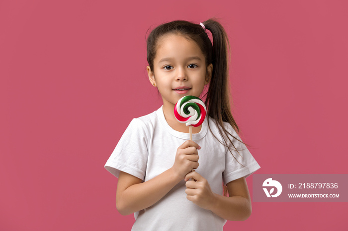 Beautiful cute little child girl with sweet candy lollipop isolated on pink background