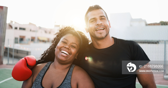 Curvy woman doing boxing exercise with her personal trainer outdoor - Focus on glove