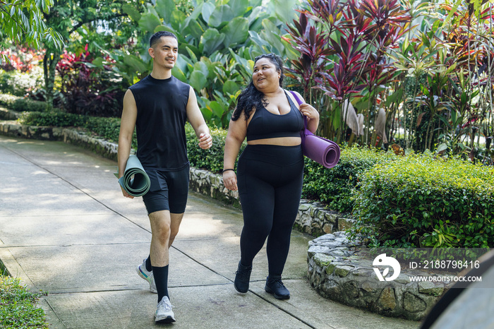 Two friends walking with yoga mats in the park