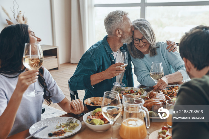 Modern multi-generation family communicating and smiling while having dinner together